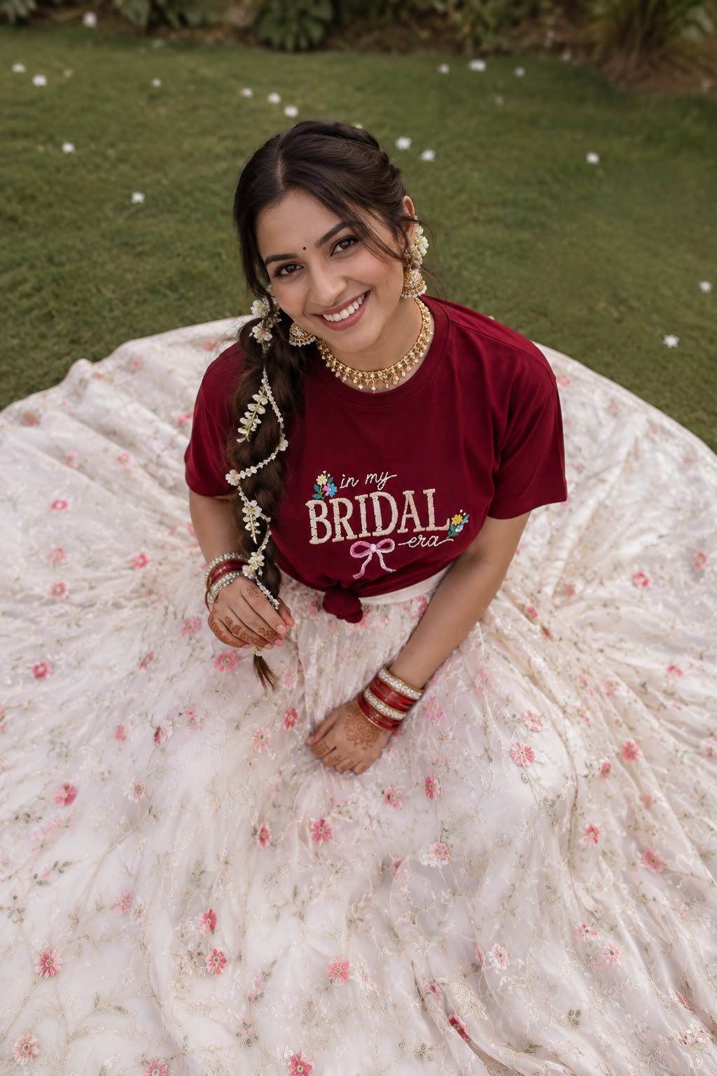 Bride-to-be in a white floral lehenga wearing the maroon In My Bridal Era hand embroidered tee, knotted at the waist